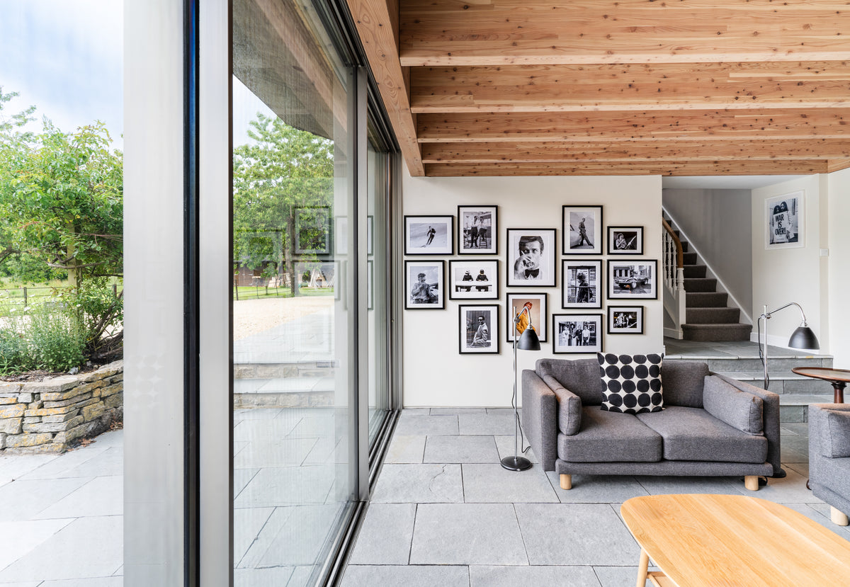 Bright open-plan living room with a grid of framed black and white photographs beside a staircase