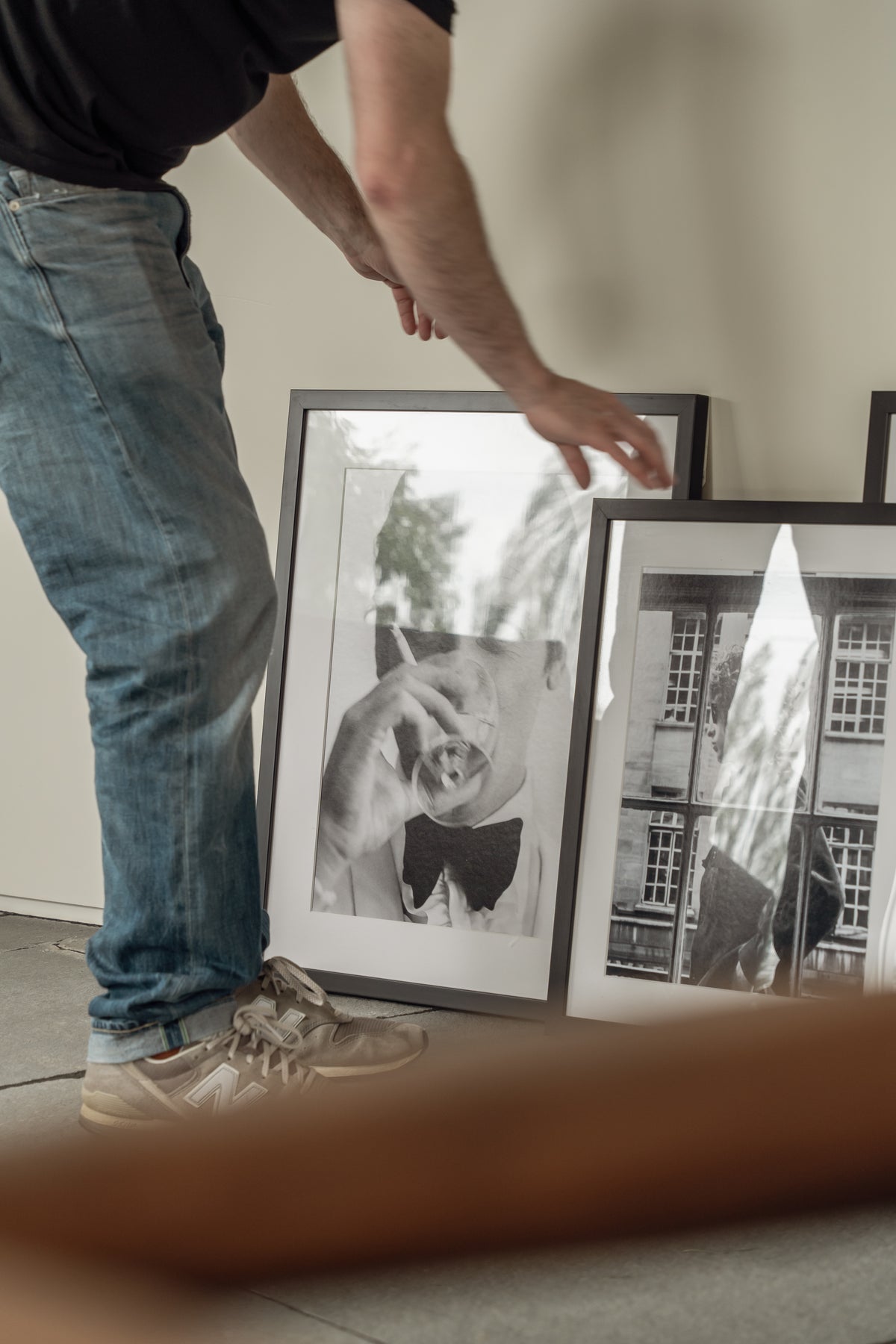 Person lifting a large framed black and white Sonic Editions print leaning against a wall